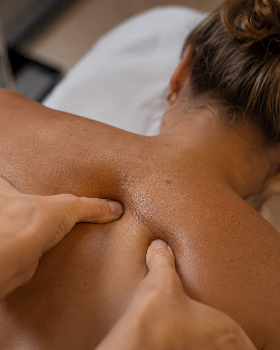 A person receiving a massage on their back and shoulder area from a massage therapist.