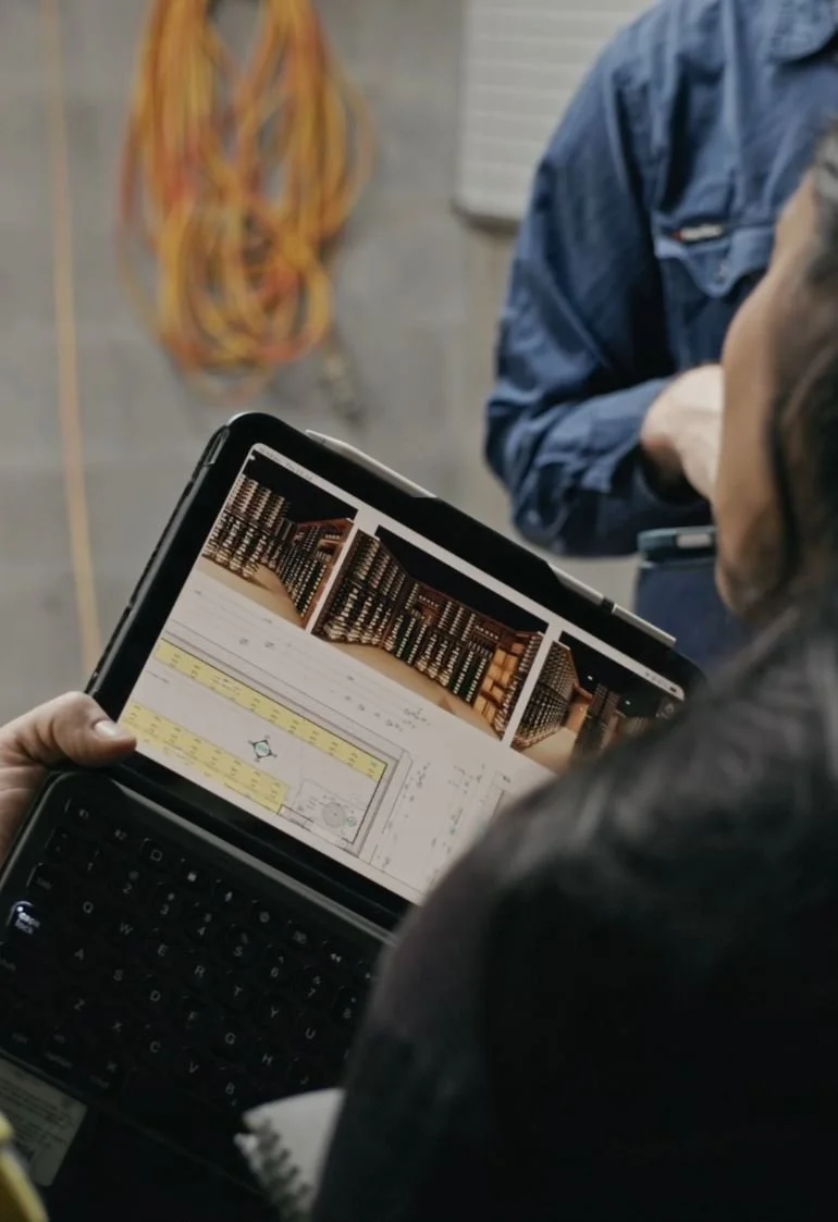 Work with AOG at site meeting displaying architectural plans and an image of a wine room design on a device.