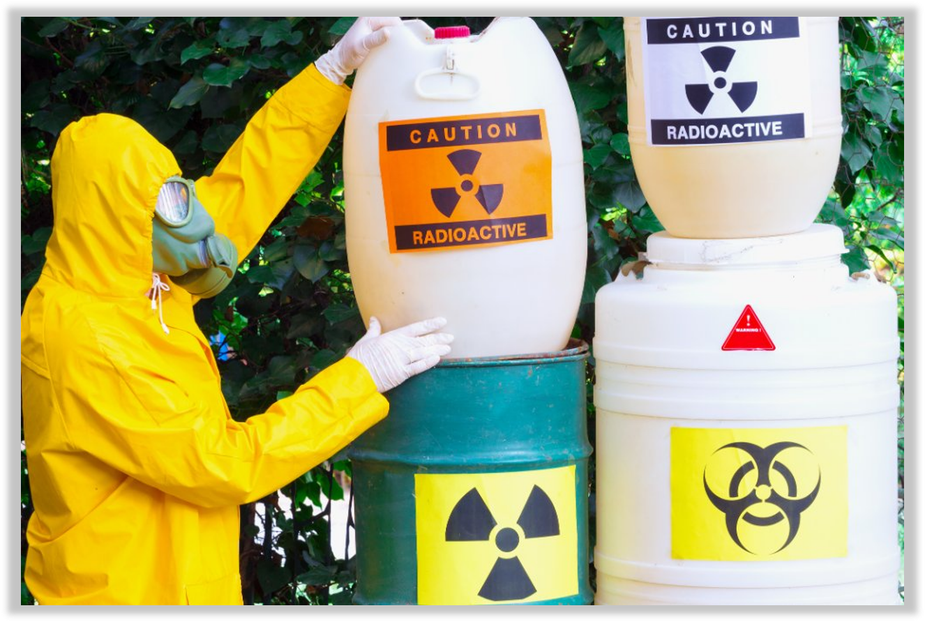 Person wearing yellow hazmat suit and mask handling containers labeled with radioactive and biohazard symbols, indicating radioactive and hazardous waste storage.