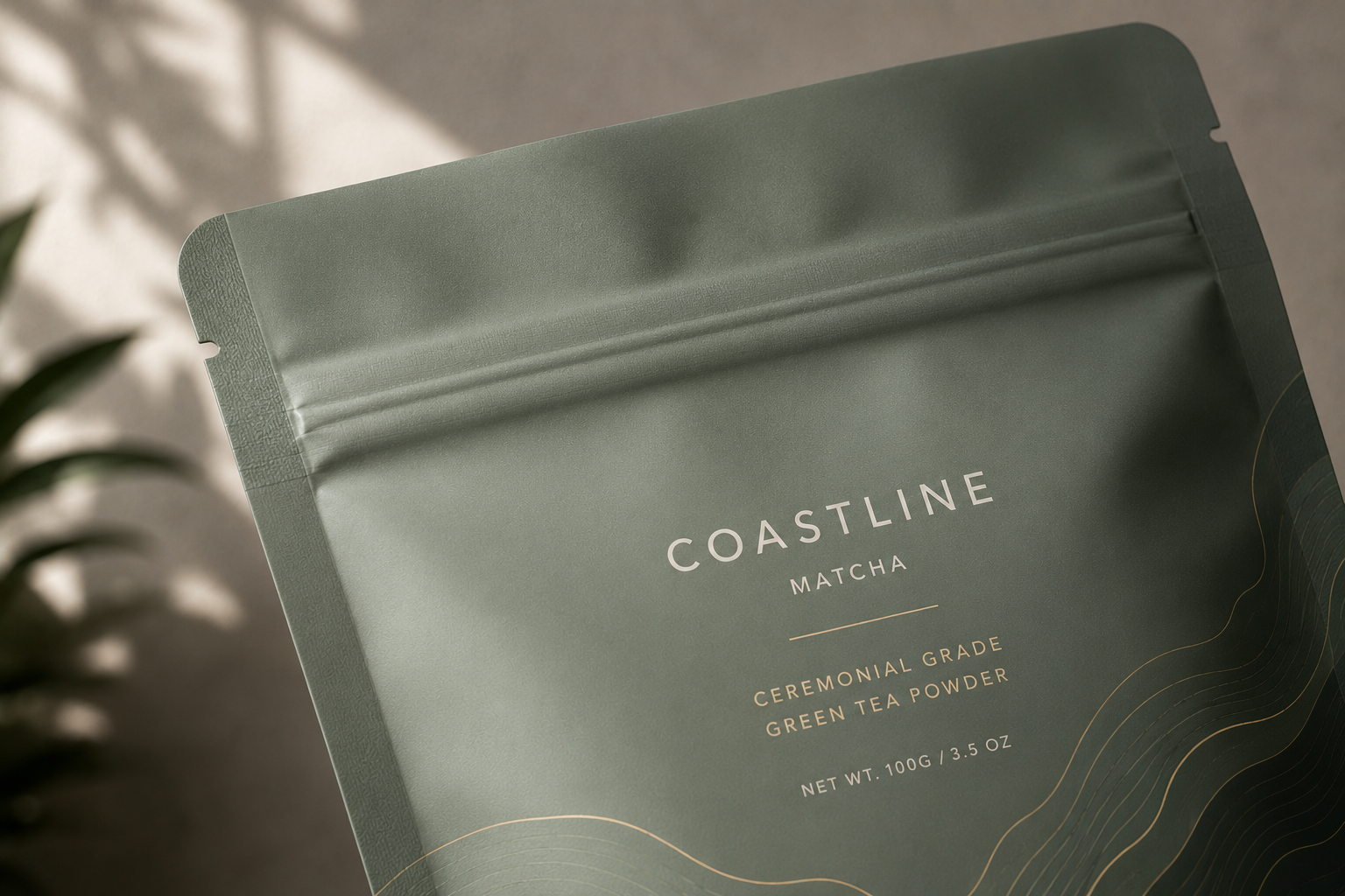 Close-up of a green tea powder package labeled 'Coastline Matcha' with additional text indicating it is ceremonial grade green tea powder, net weight 100 grams, 3.5 ounces.
