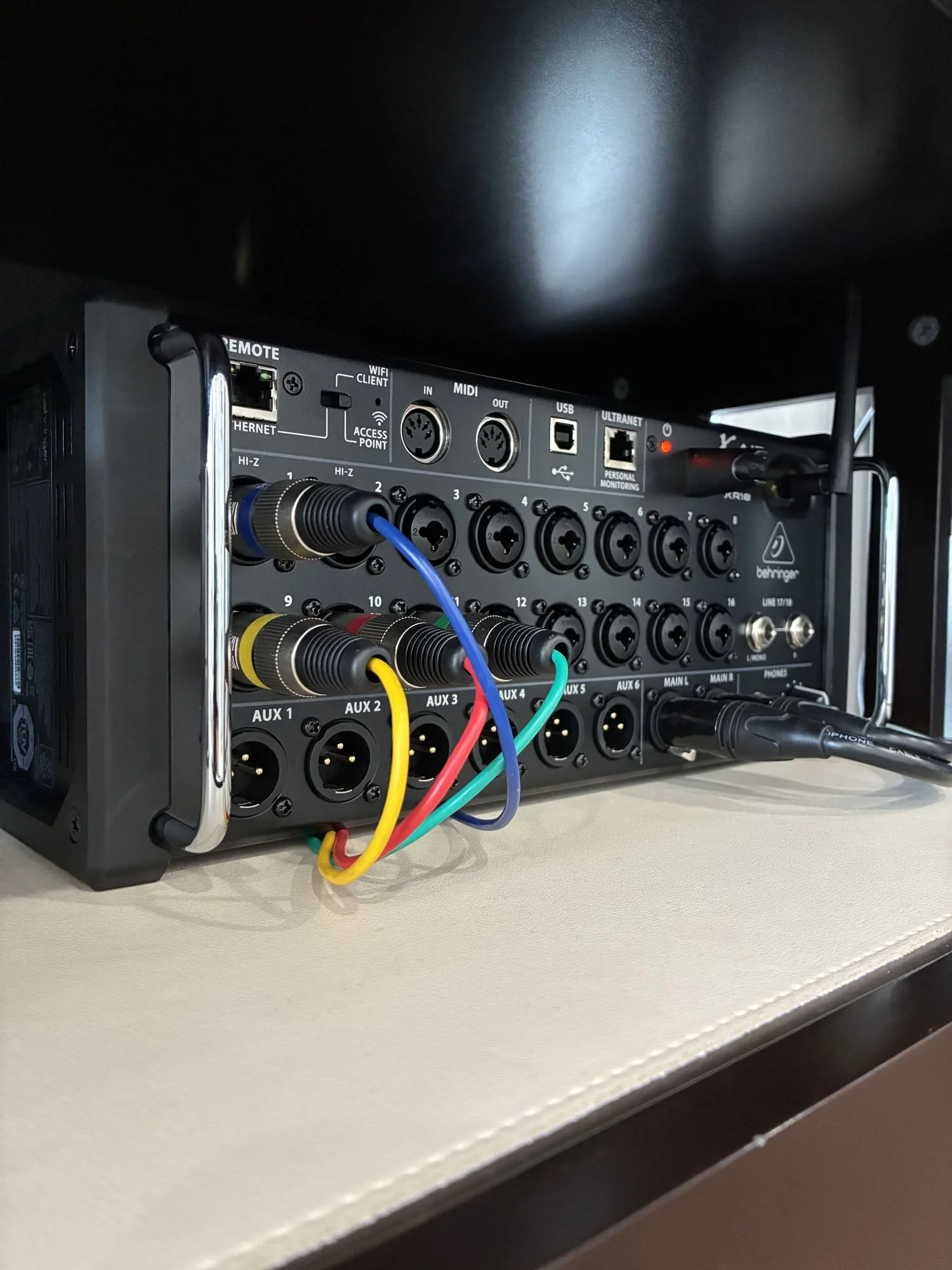 Close-up view of audio equipment with various cables connected, including yellow, red, blue, and green wires, on a white surface with a black background.