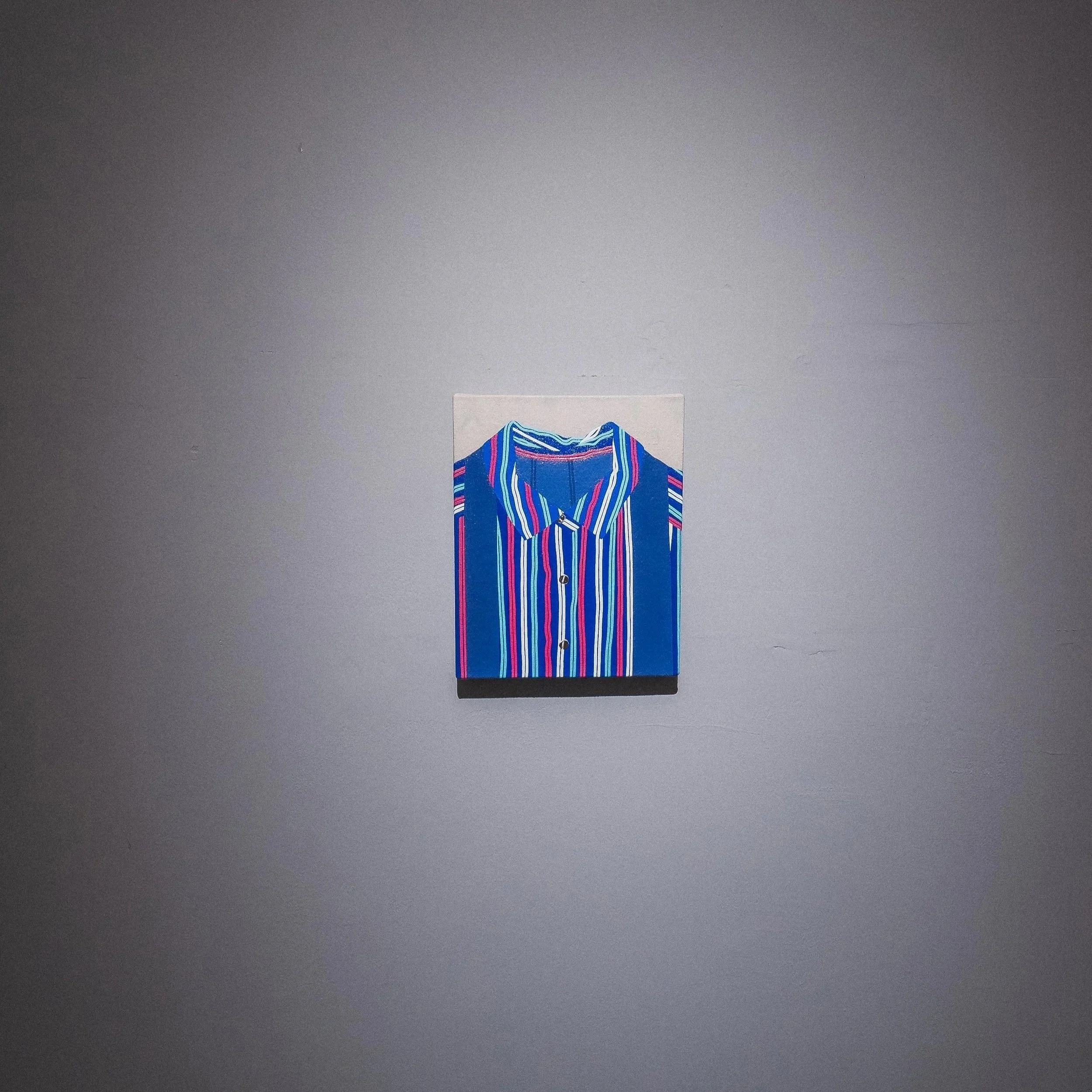 Colorful striped men's dress shirt hanging on a wall.