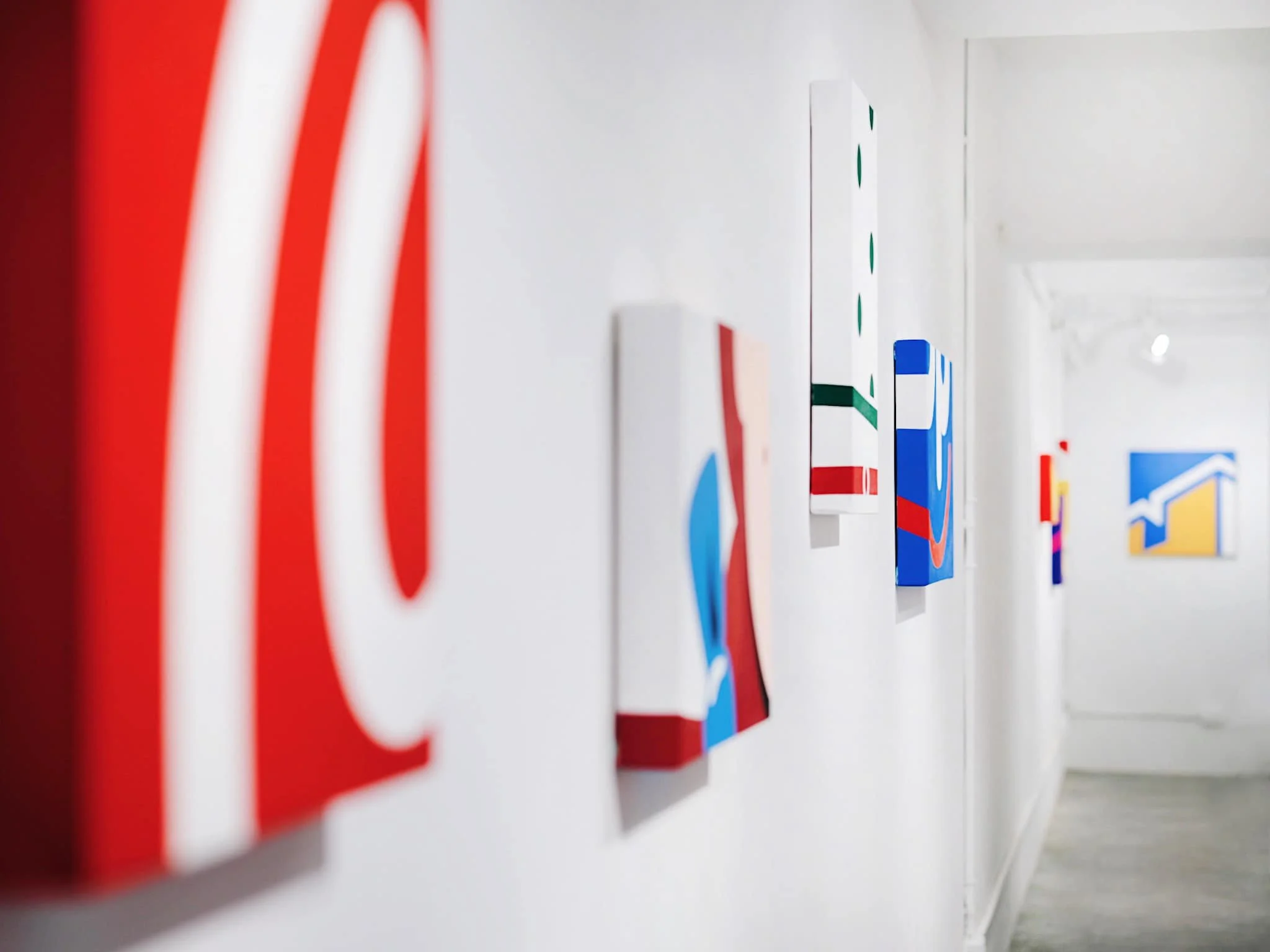 Colorful alphabet blocks on a white wall or shelf, with a blurred background