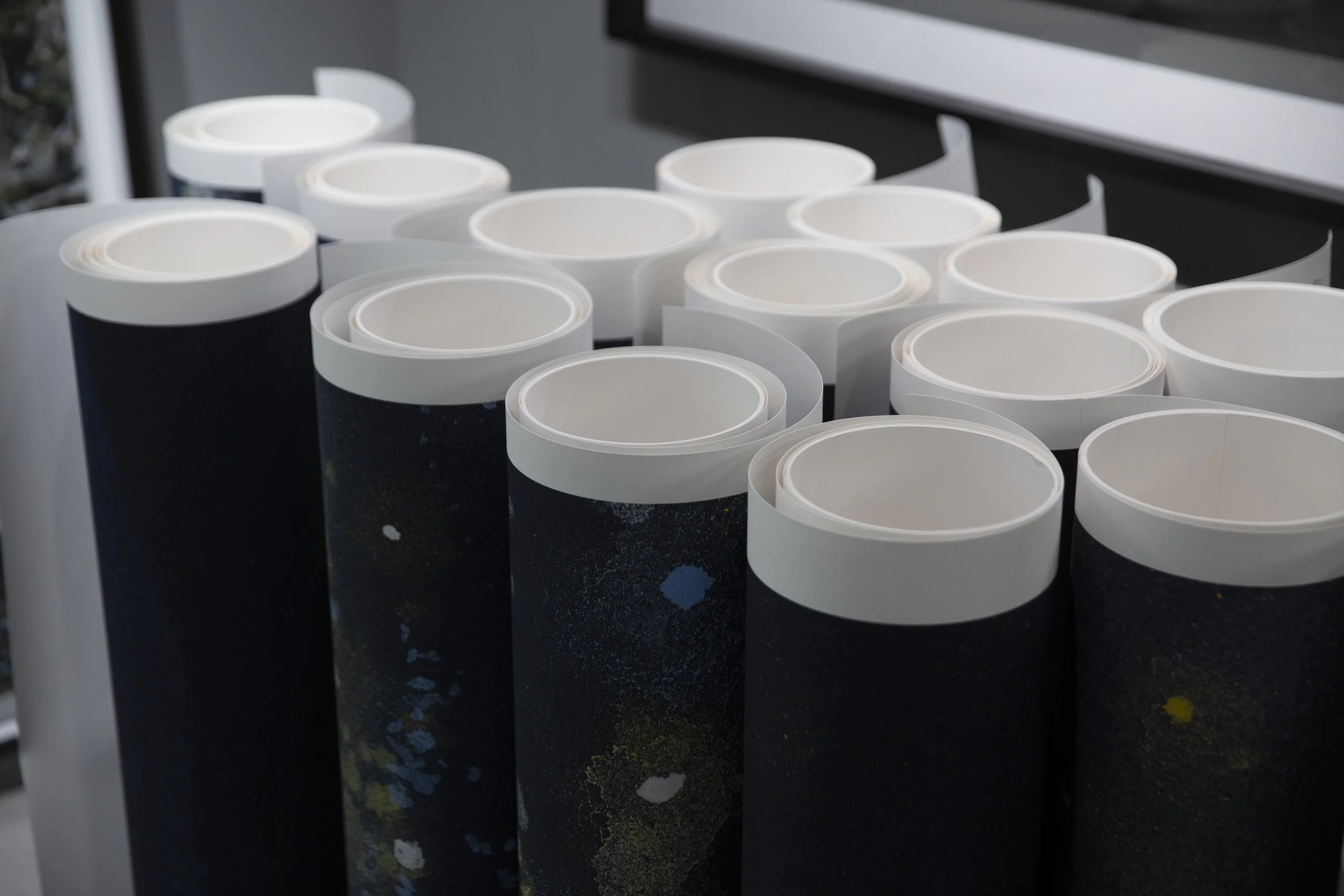 Multiple white and black rolls of adhesive tape or paper arranged on a surface.