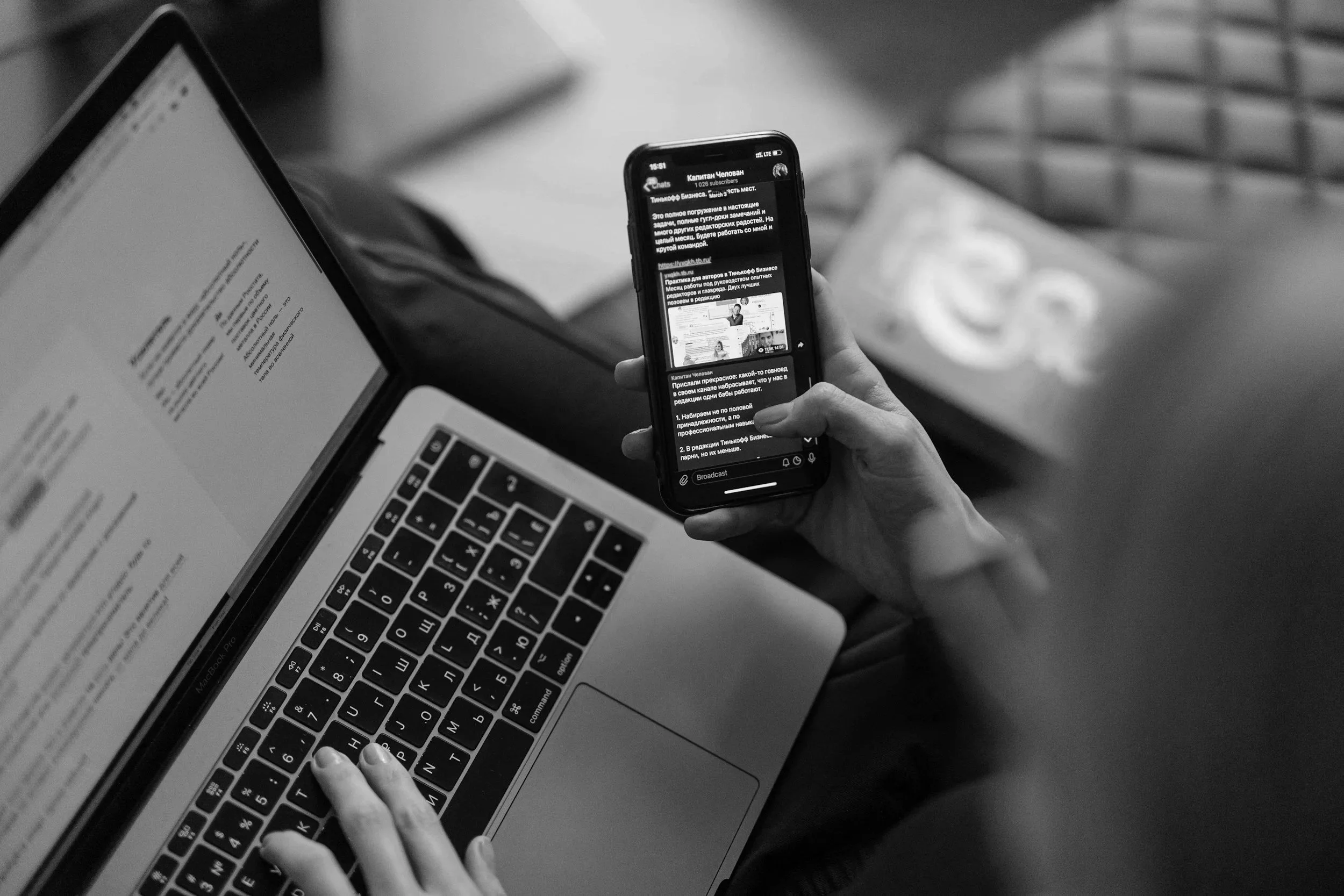 Marketer writing an email on a laptop while checking messages on a phone