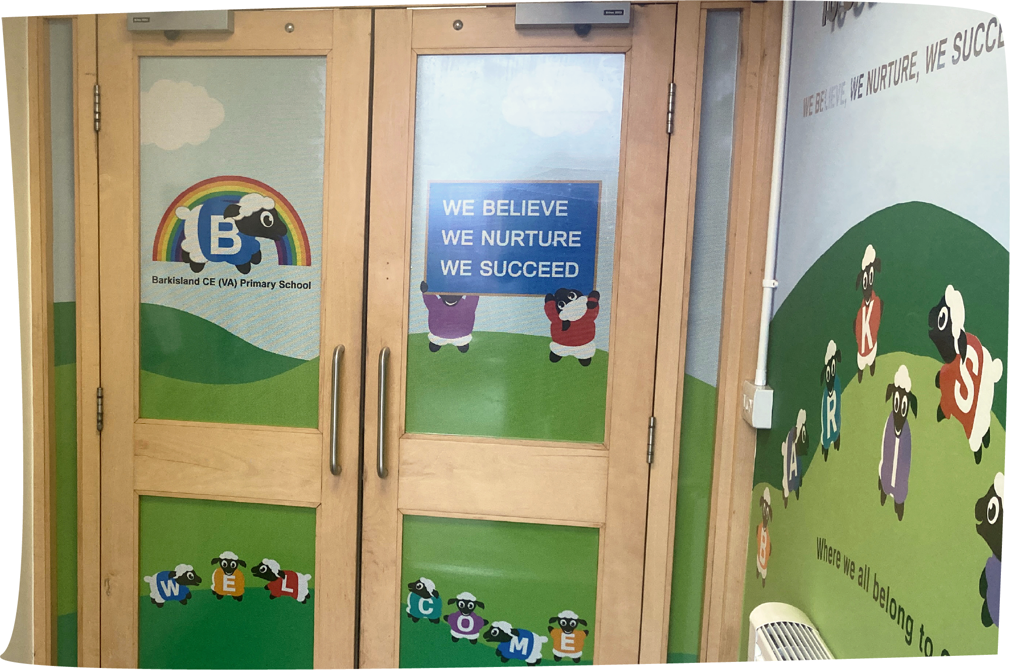 Wooden doors with eye-catching privacy window vinyls covering the glass panels The colourful illustrations feature Barkisland Primary School's sheep characters in a countryside scene promoting the school’s values and mission statement.