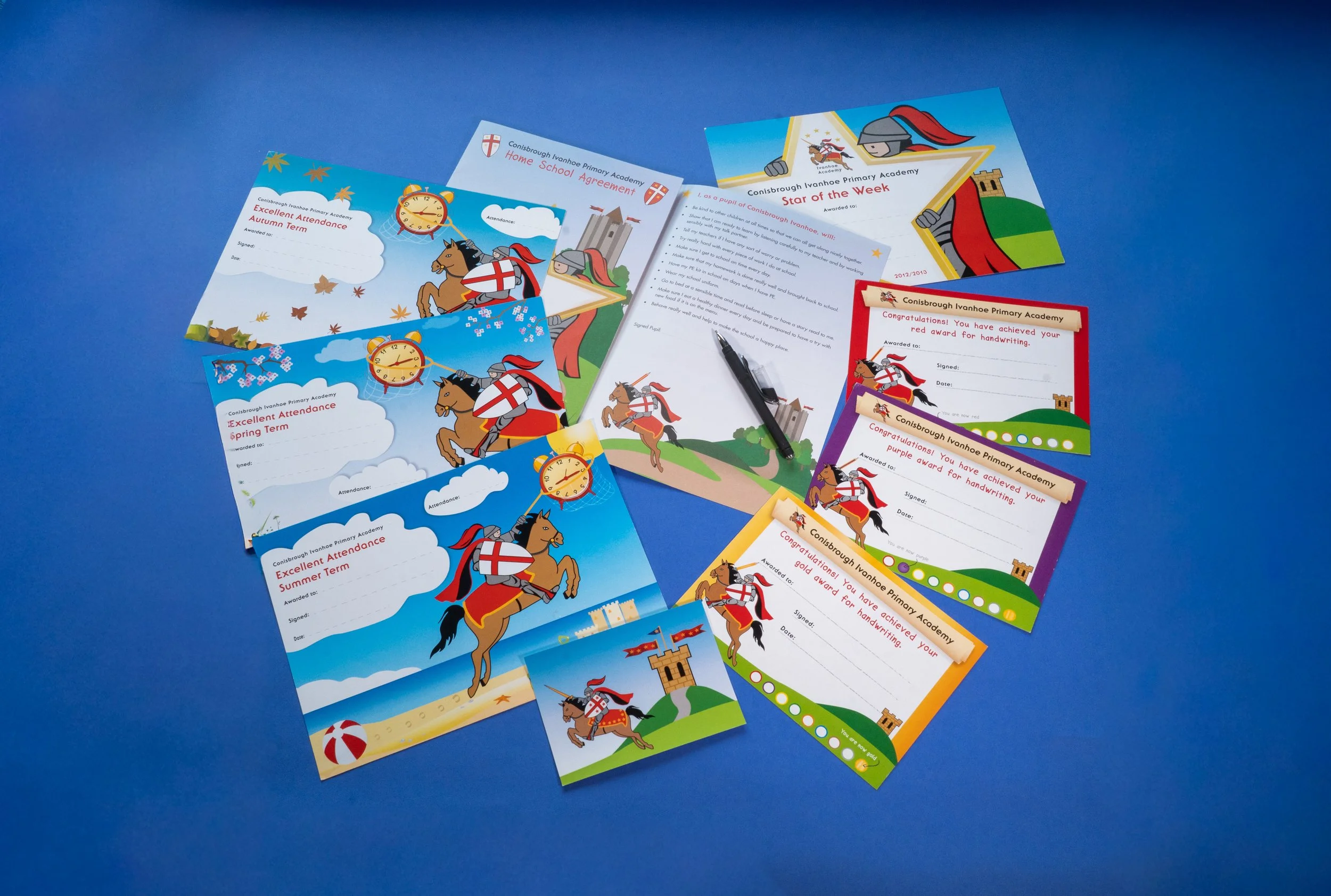 Colorful school achievement certificates and awards for Conisbrough Ivanhoe Primary Academy laid out on a blue background.