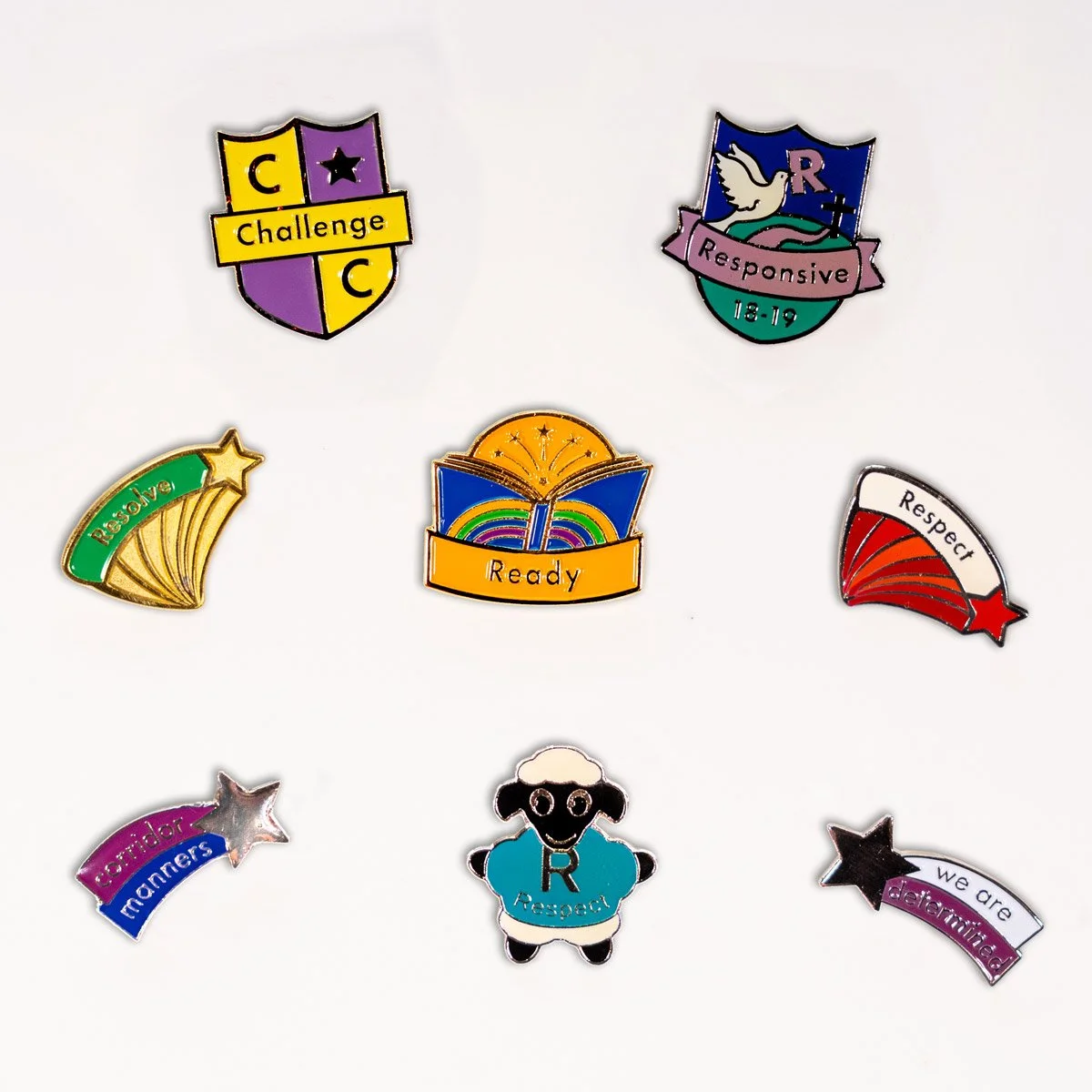 A collection of colorful pins with motivational and respectful messages such as 'Challenge', 'Responsive', 'Resolve', 'Ready', 'Respect', 'Caring for manners', and 'We are determined' arranged on a white background.