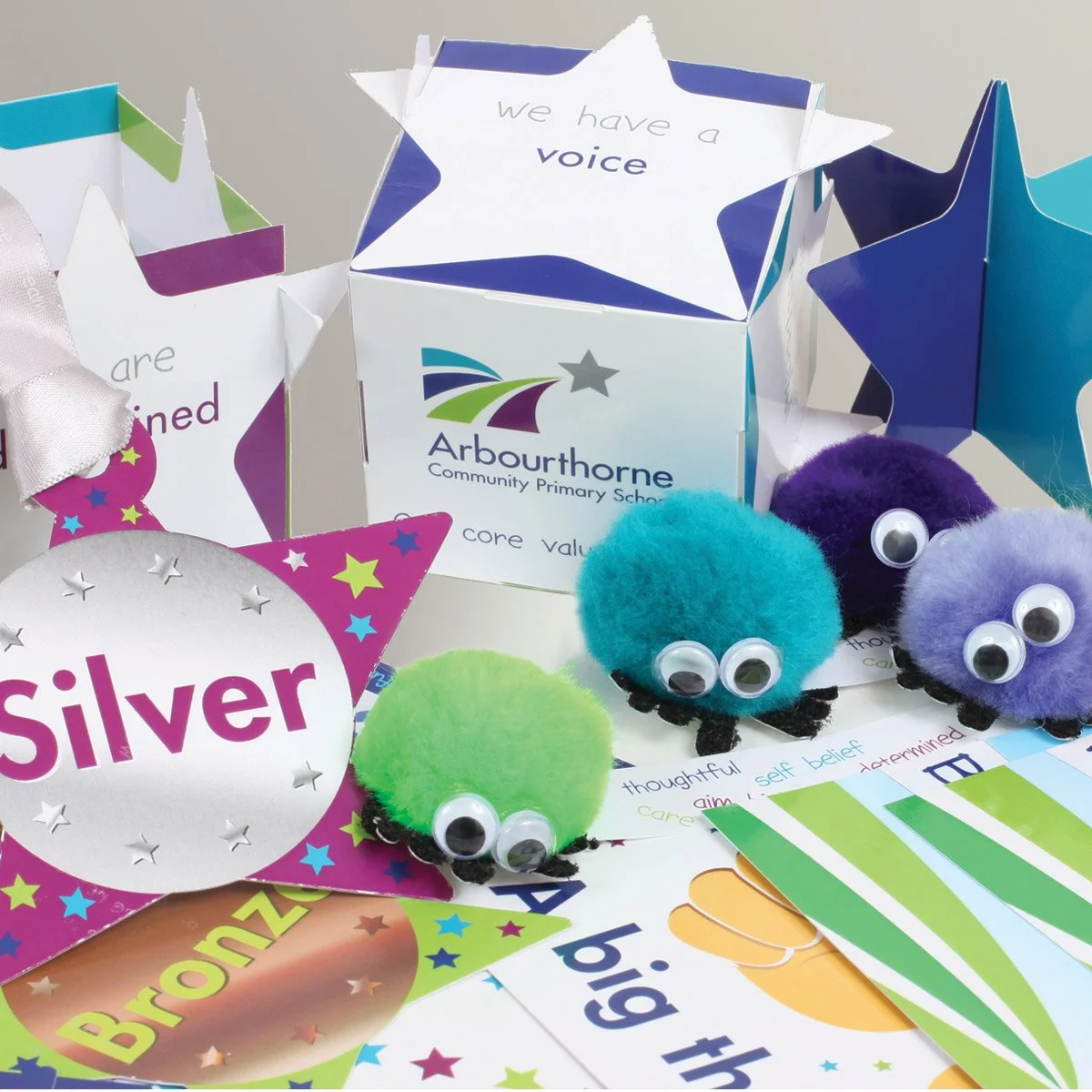 Colorful educational materials from Arbourthorne Community Primary School including plush toys with googly eyes, star-shaped signs, and printed charts promoting core values and learning concepts.