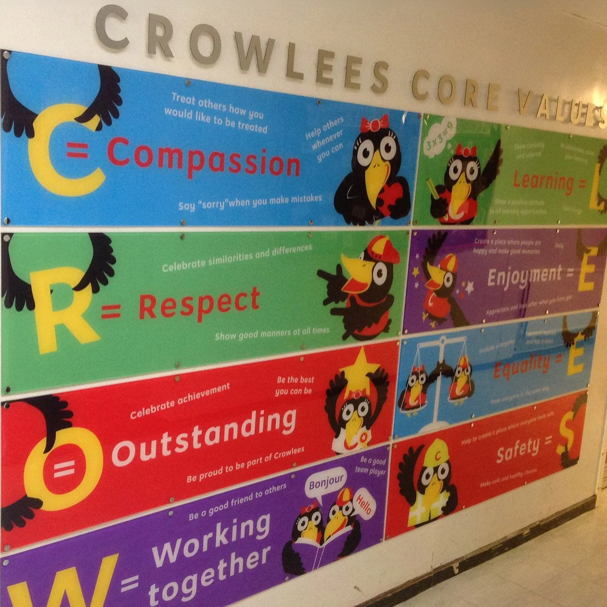 Colorful educational poster displaying the core values of CROWLEES, with each value represented by a cartoon crow and a letter. The values are Compassion, Respect, Outstanding, Working together, Learning, Enjoyment, Equality, and Safety, each with a brief description.