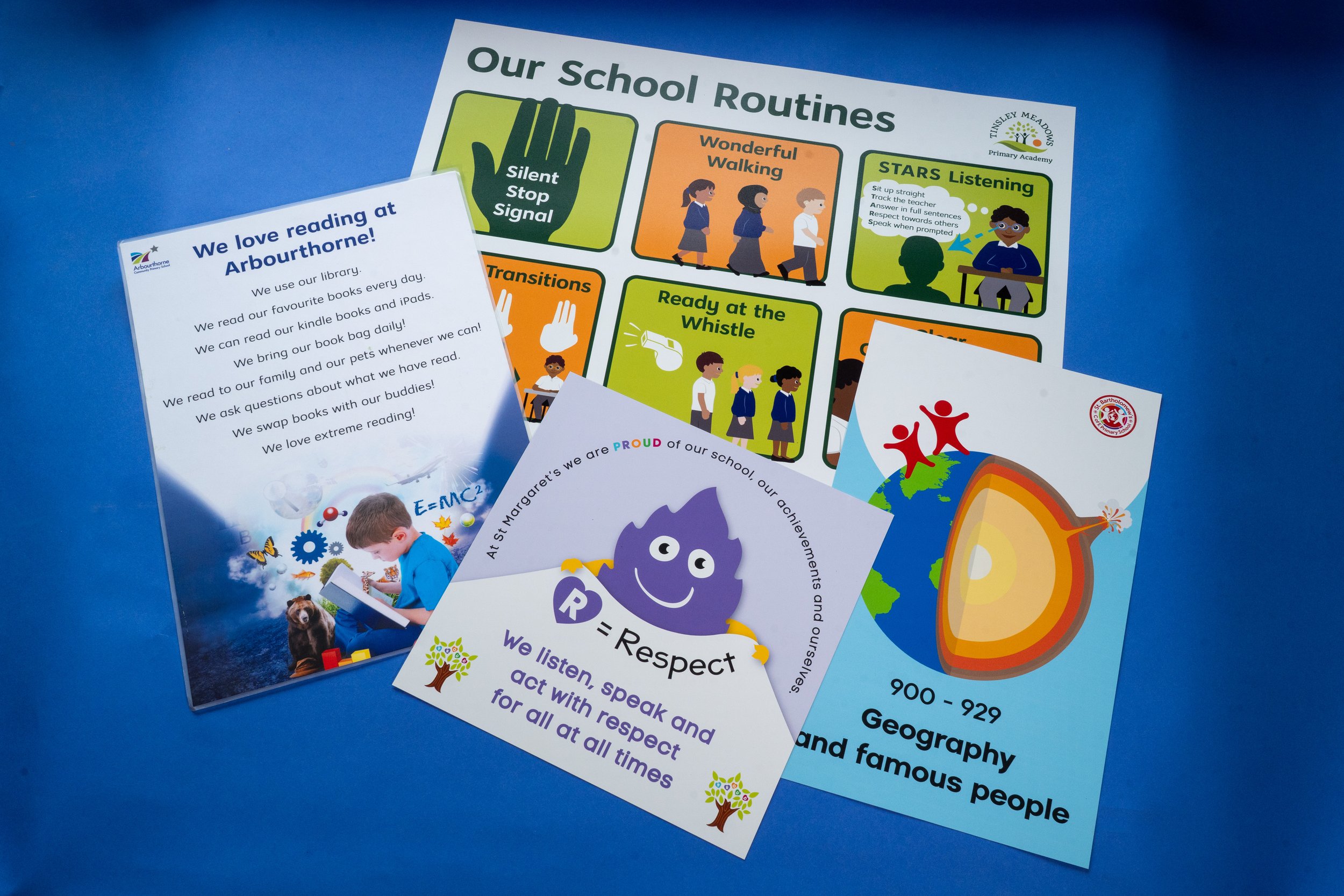 Collection of colorful school flyers and posters on a blue background, including a poster titled 'Our School Routines' with illustrations and a white flyer titled 'We love reading at Arbourthorne' with text about library habits.
