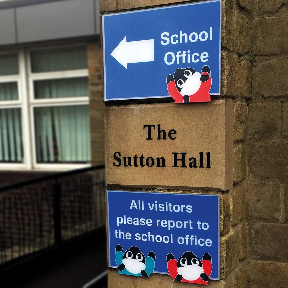 Sign indicating the direction to the school office, with a cartoon panda mascot and text instructing visitors to report to the school office.