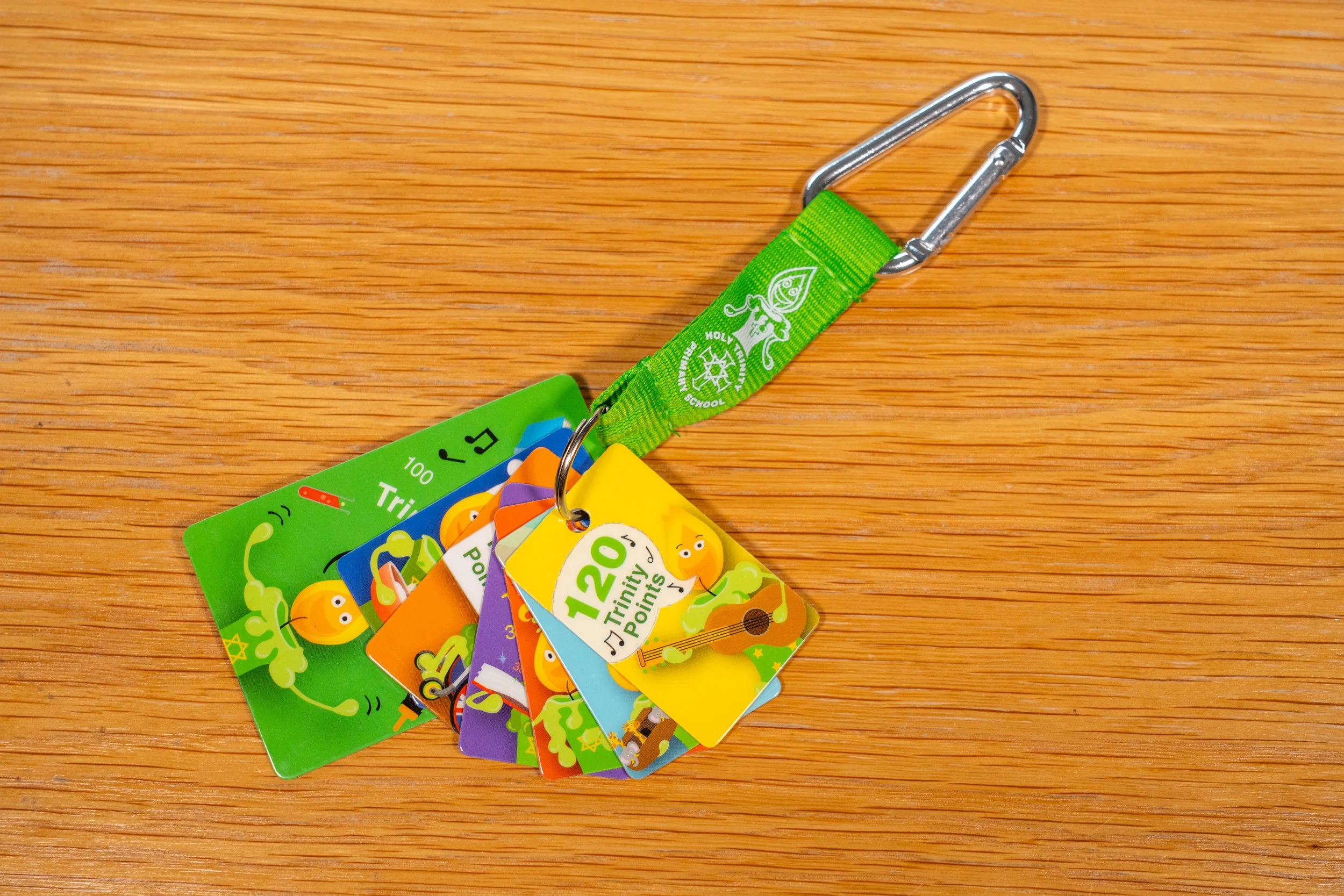 Colorful educational cards connected by a green strap with a carabiner clip, displayed on a wooden surface.