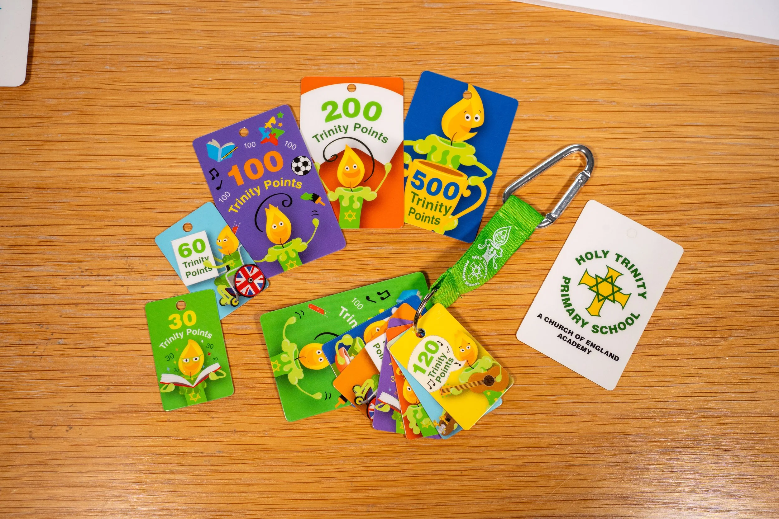 Colorful church award and achievement badges with Trinity Points on a wooden surface.