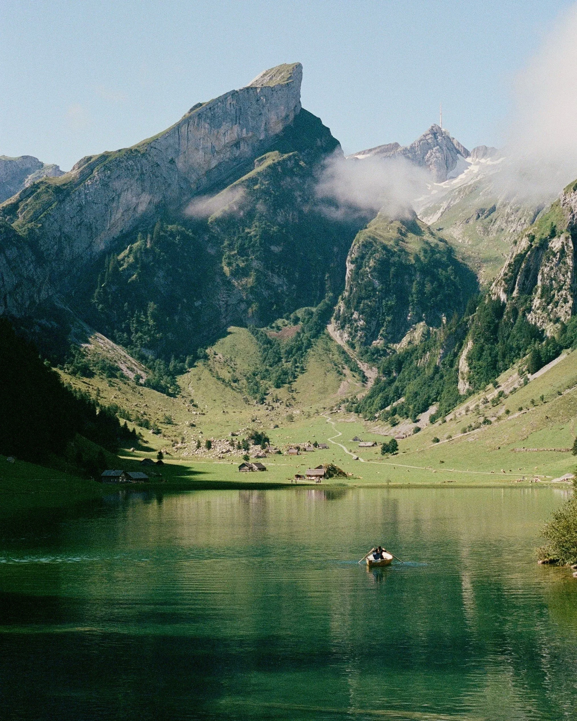 A lone rowboat crosses Seealpsee, framed by the jagged peaks of the Alpstein massif in Appenzell, Switzerland.