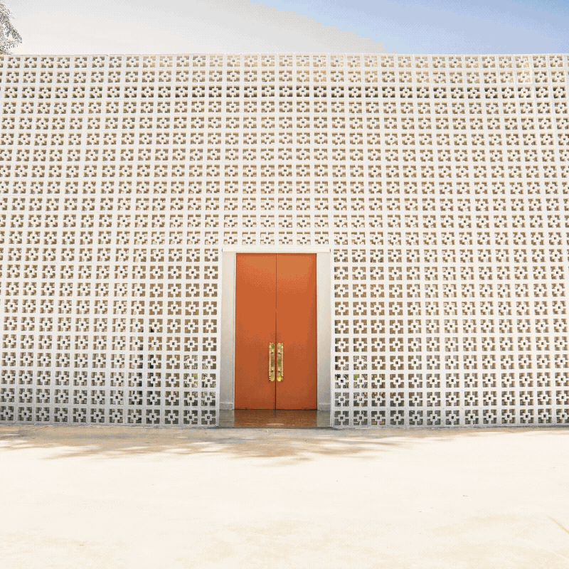 Bright orange double doors set into the breeze-block facade at The Parker Palm Springs.
