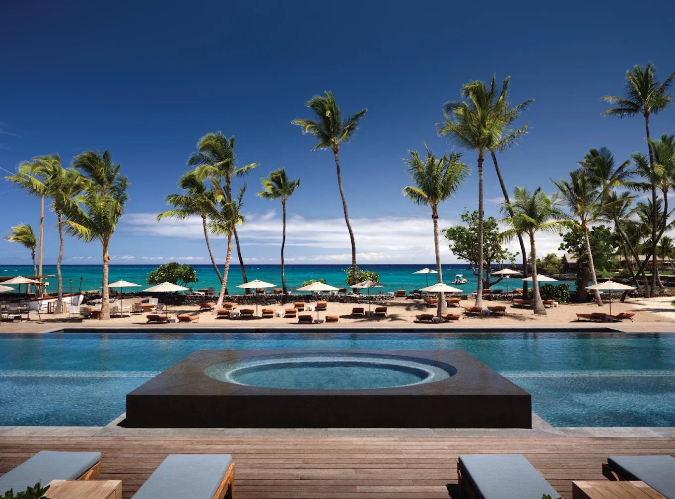 Rosewood Kona Village, Big Island Hawaii. Pool overlooking the ocean with a hot tub and palm trees.