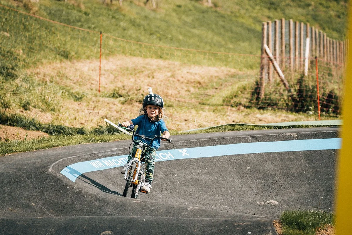 Ein Kind fährt auf einem Fahrrad auf einem Pumptrack.