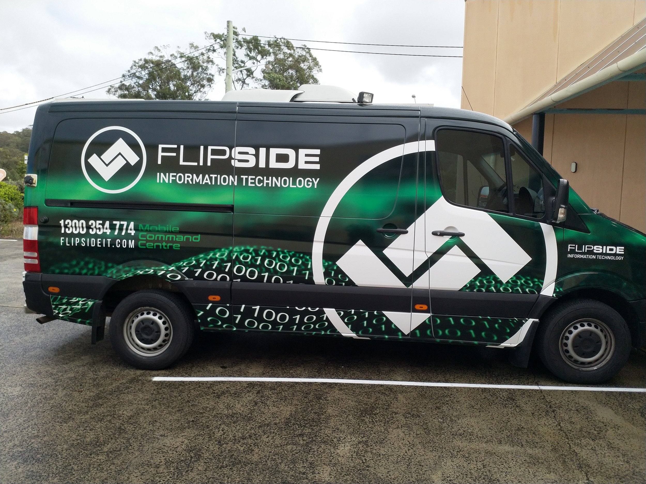 A black and green delivery van with the logo and branding of Flipside Information Technology, parked in an outdoor parking lot on a cloudy day.