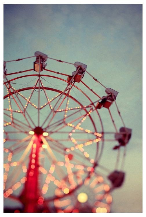 A Ferris wheel at an amusement park with lights glowing against a twilight sky.