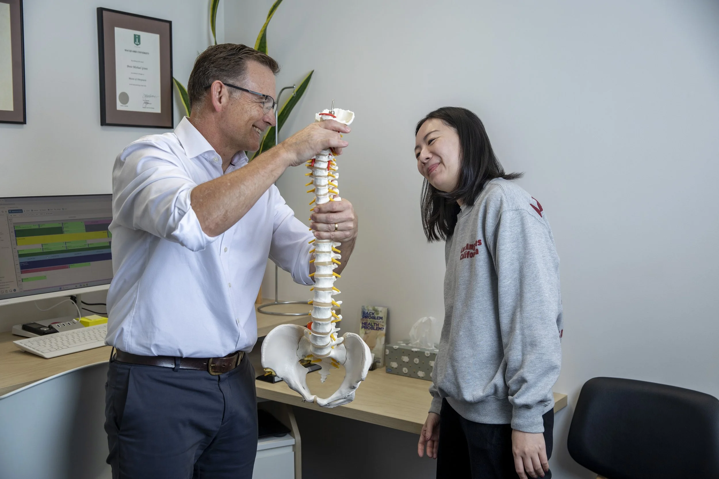 Dr Brett Grant performing a chiropractic neck assessment and explanation on a patient with recurring headaches at Family Chiropractic Chatswood