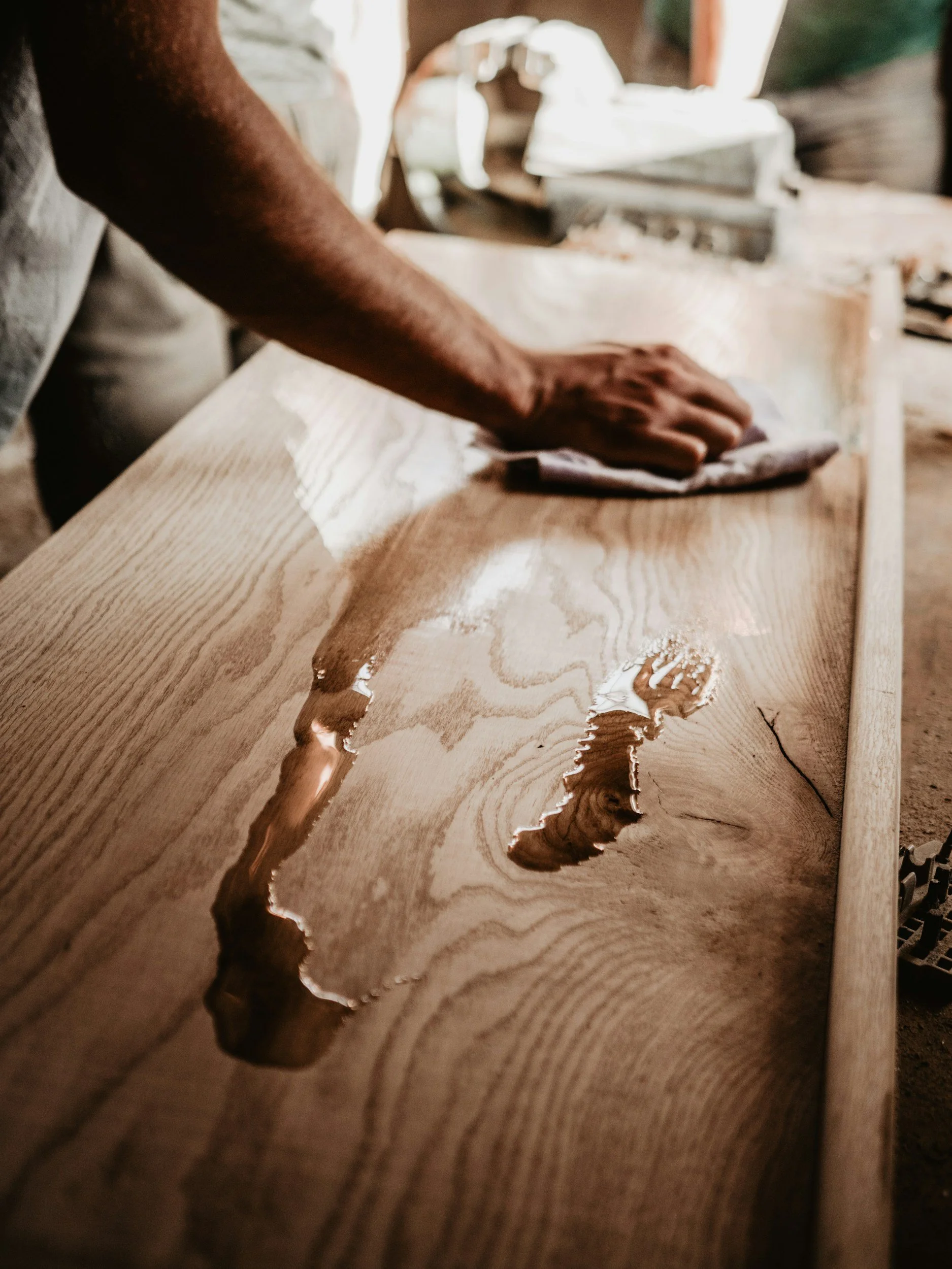 Person sanding a wooden surface in a woodworking shop.
