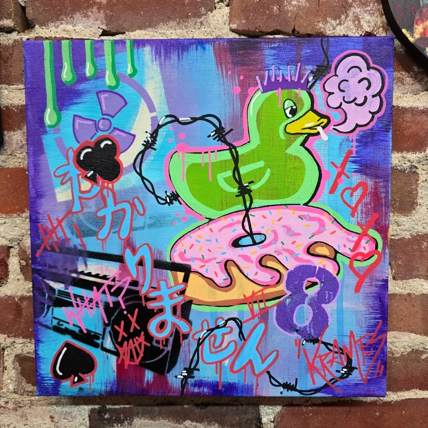 A colorful graffiti-style painting featuring a cartoon duck with green feathers, a yellow beak, and purple spiked hair, sitting on a pink donut with sprinkles. The duck is smoking a cigarette, surrounded by various symbols and tags, including a skull