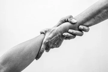 Two hands shaking, one appearing older and the other younger, symbolizing agreement or partnership in black and white.