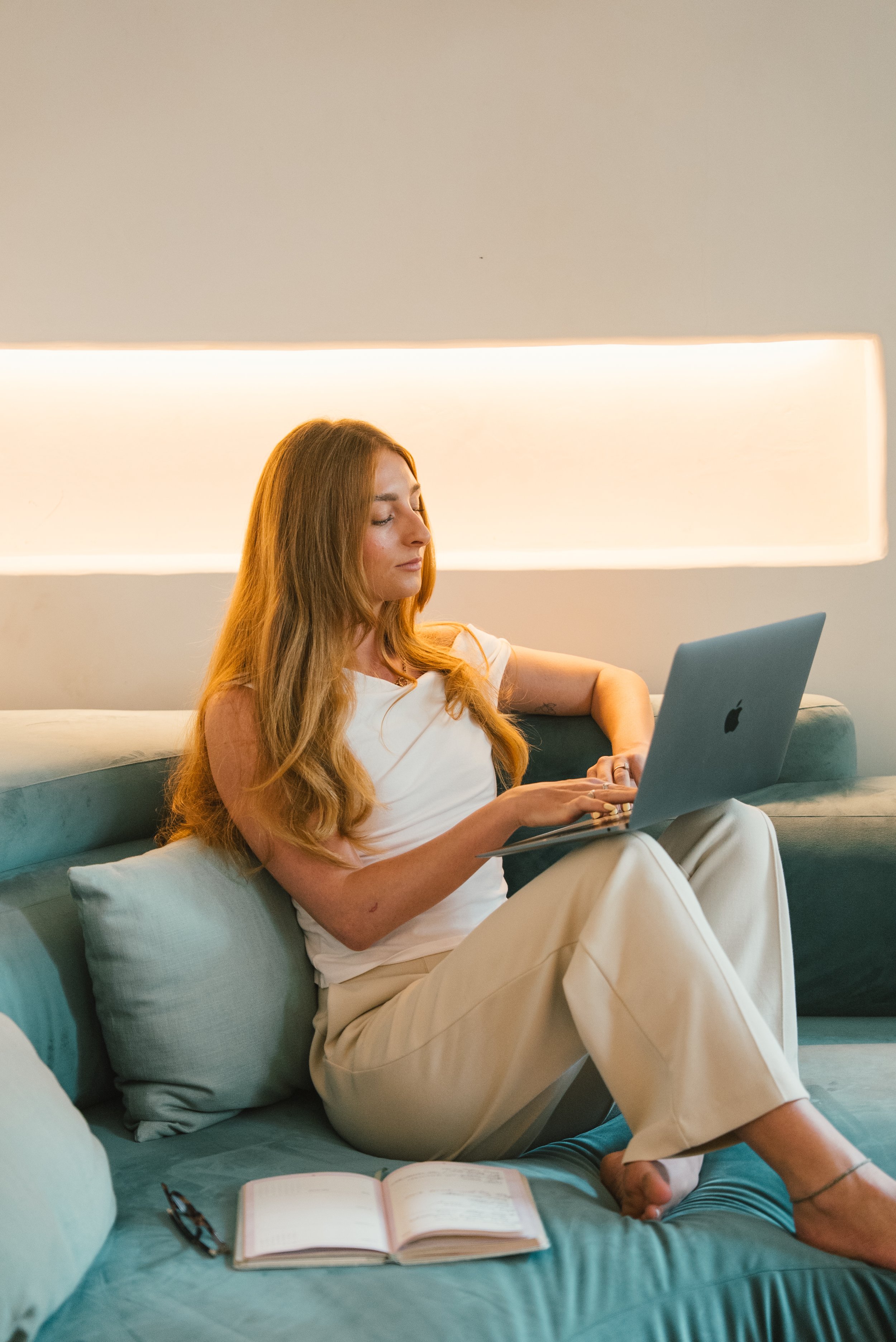 Travel advisor planning trips from bed with laptop and notes.