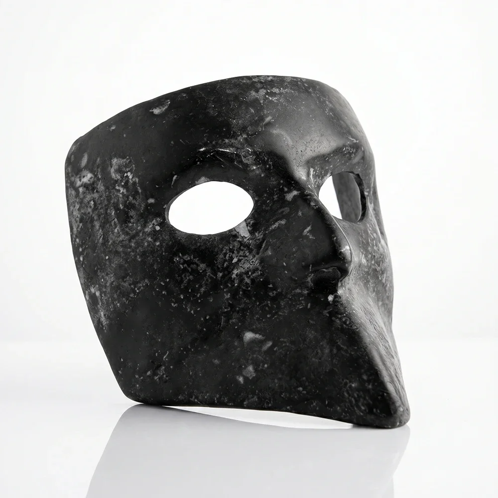 Maschera scultorea dal profilo affilato, firmata Ivan Ricupero. Magnesite nera esalta l'affioramento organico e la cristallizzazione dei sali marini sulla superficie. Un ritratto in still life su fondo bianco.