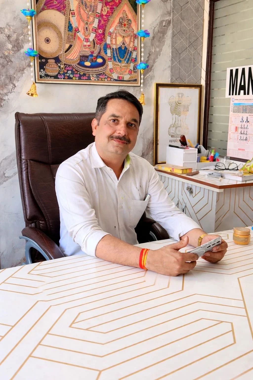 Advocate Manoj Rana in his Court Chamber. The Chamber has framed artwork and decorative items on the walls, with office supplies on the desk.