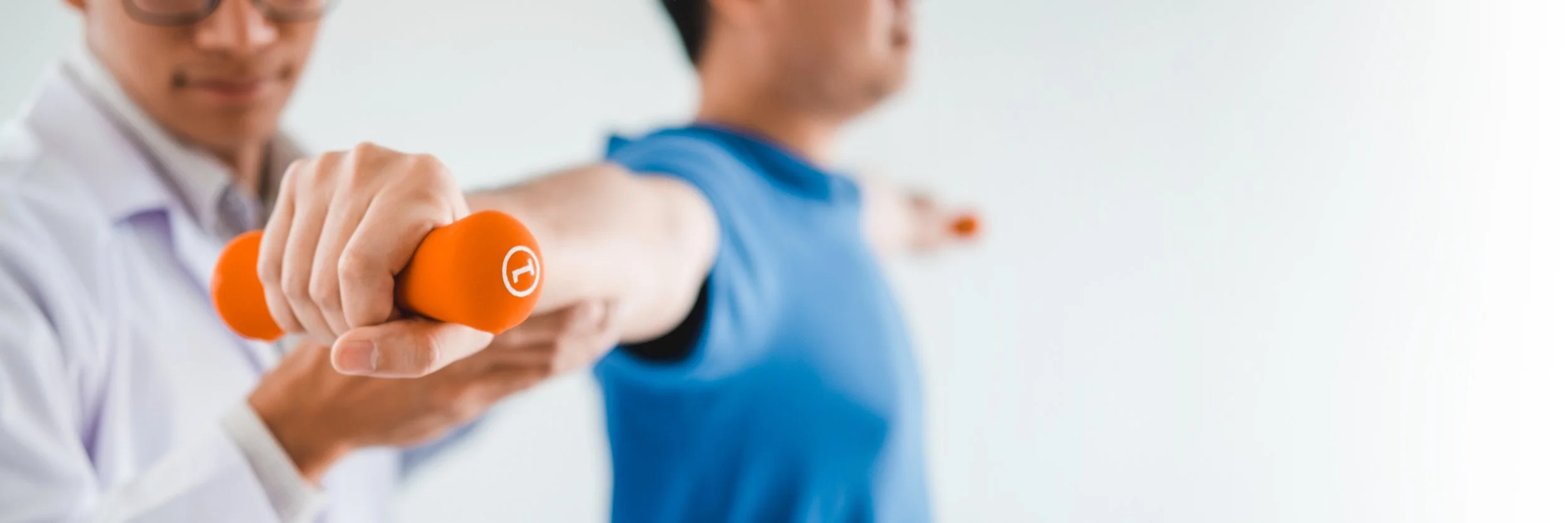 A fitness instructor assisting a person with stretching arm exercise, holding orange dumbbell in a bright room.  Personal Training for the over 50's. Ramsbury, Wiltshire.