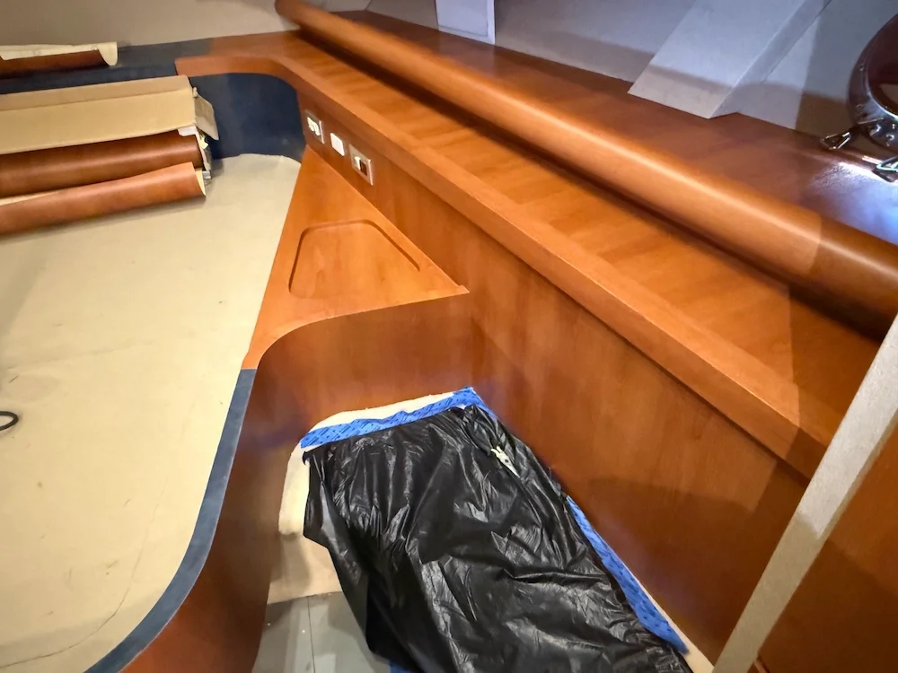 A wooden dance floor or stage under construction or renovation, with rolls of material on the side and a plastic-covered item on the floor.