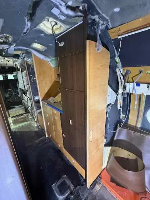 Interior of a damaged vehicle with a wooden table and various debris scattered around.
