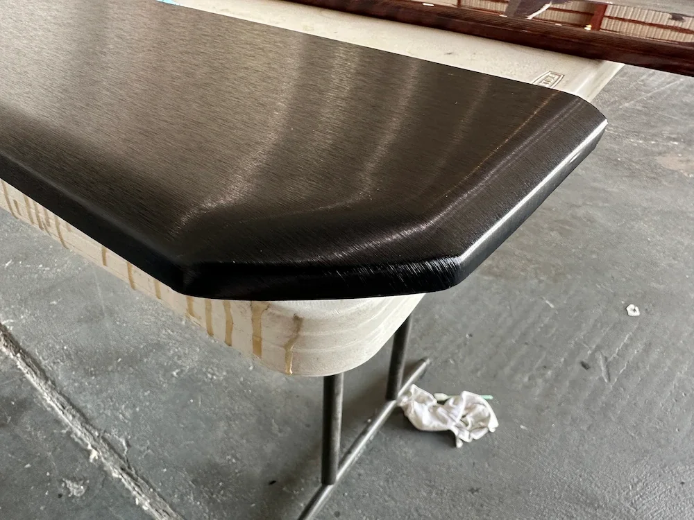 Close-up of a black countertop over a white base with yellowish streaks, supported by metal legs, on a rough concrete floor with a crumpled white cloth underneath.