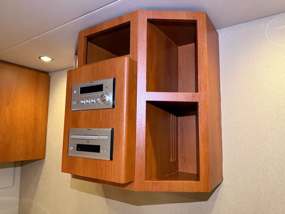 Wooden cabinet with electronic controls and empty shelves mounted on a wall.