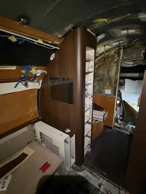 Interior of an airplane cabin with seats, overhead compartments, and a curved wall.