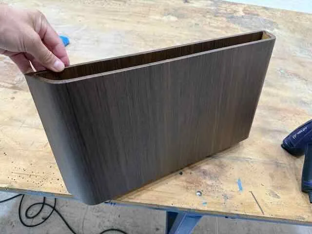 A hand holding a wooden rectangular box in a workshop.