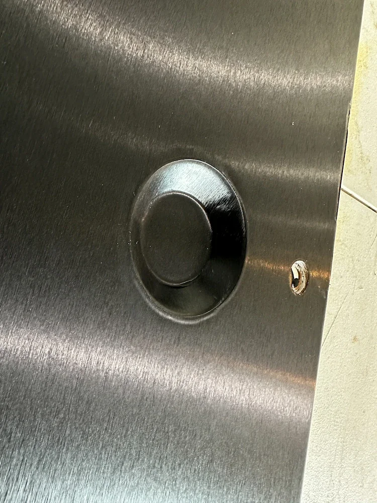 Close-up of a metallic surface with a circular button and a keyhole.