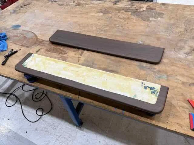 A skateboard with a partially removed graphic on its deck, placed on a wooden workbench.