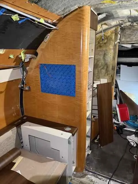 Wooden desk with a blue mat, surrounded by various tools and materials in a workshop or construction area.