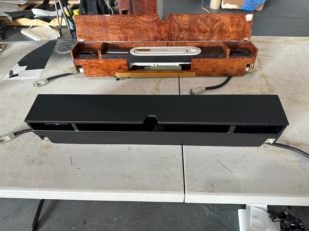 Two vintage slide projectors, one with a woodgrain finish and one black, placed on a worktable in a workshop setting.