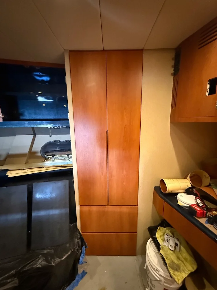 Wooden cabinet in a room with various tools and items on the countertop and a bucket on the floor.