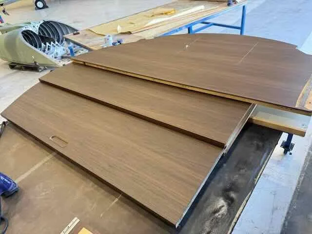 Stacked wooden panels with a dark wood finish on a work table in a woodworking shop.