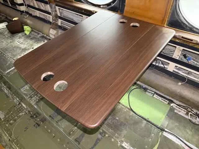 Wooden table with four circular holes in a partially disassembled vehicle interior.