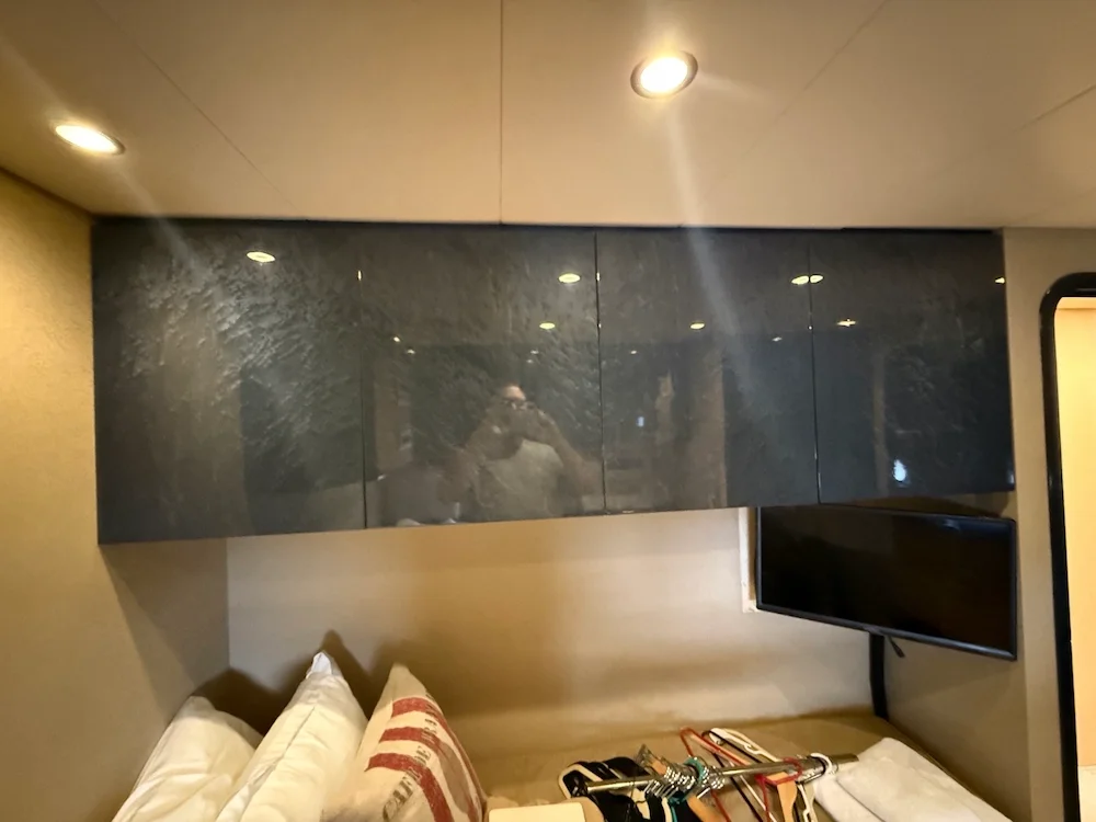 Bedroom with bed, pillows, TV, and overhead cabinets