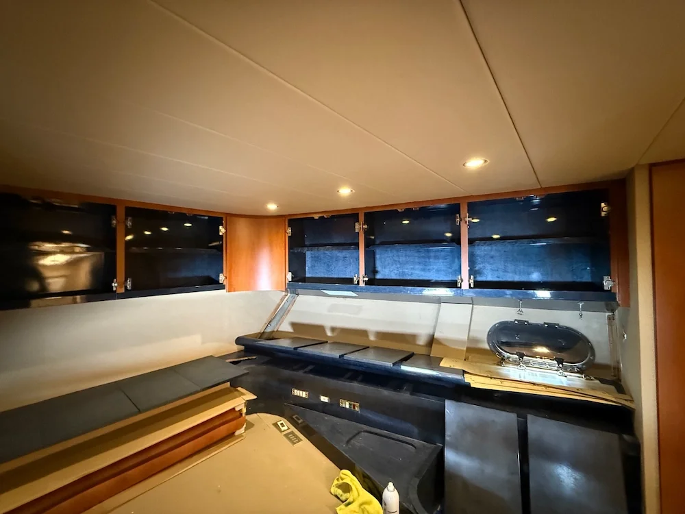 Interior of a boat or RV with cabinets, a cushioned bench, and a small sink installed.