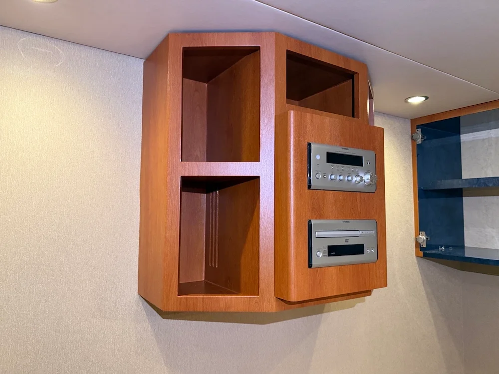 Wooden wall cabinet with two open shelves and two electronics panels mounted on the front