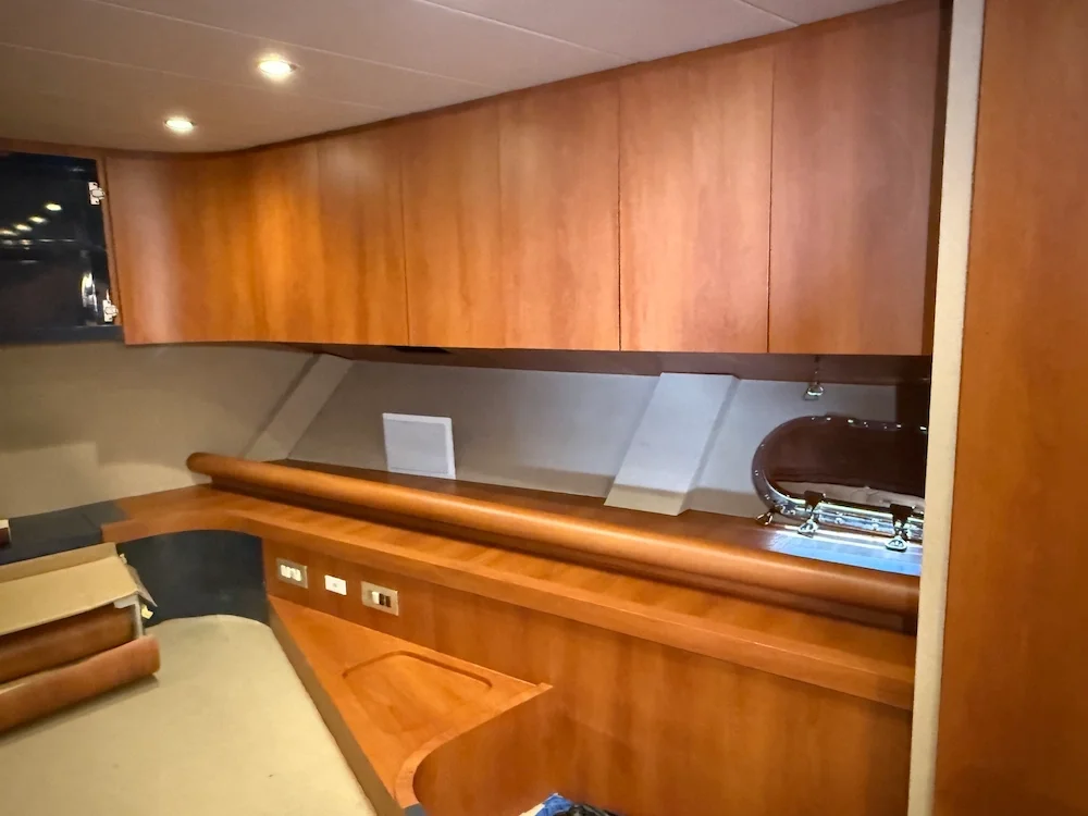 Interior of a boat cabin with wooden walls and cabinets, a small sink, and electrical outlets.