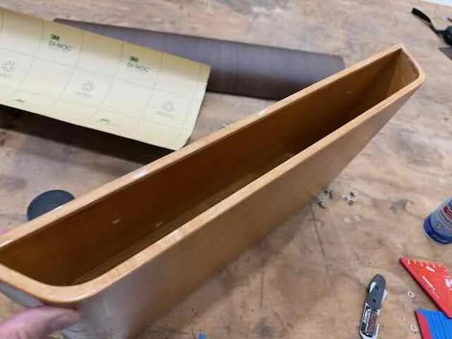 A long wooden planter box on a workbench with various tools and materials nearby.